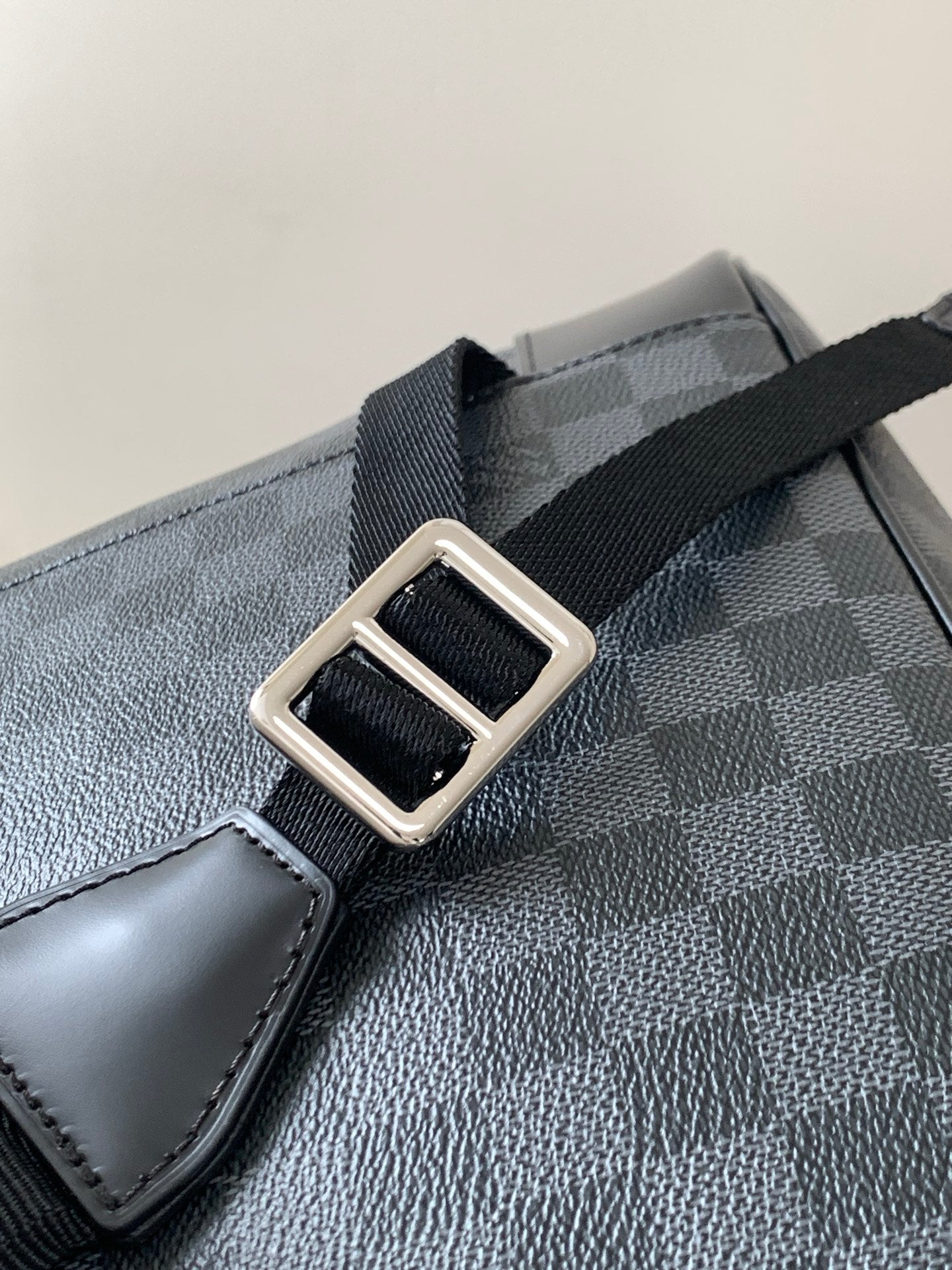 Men's Louis Vuitton checkered bag strap close-up with silver-tone buckle hardware