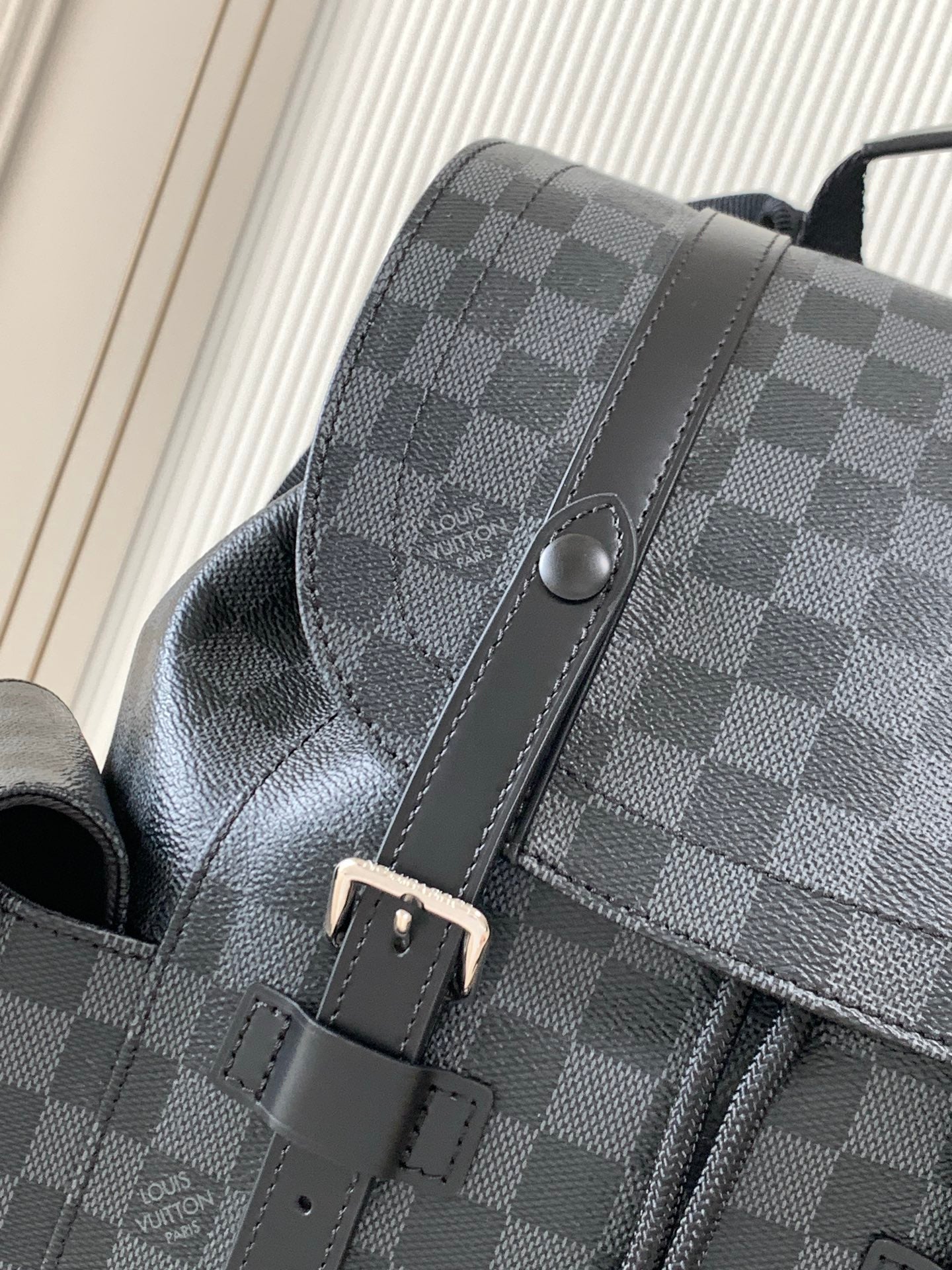 Men's Louis Vuitton checkered bag close-up with leather trim and magnetic snap tab