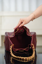 Chanel quilted bag in dark red with open top showing interior lining and gold chain trim