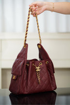 Chanel quilted shoulder bag in dark red held by gold chain strap; CC logo at front