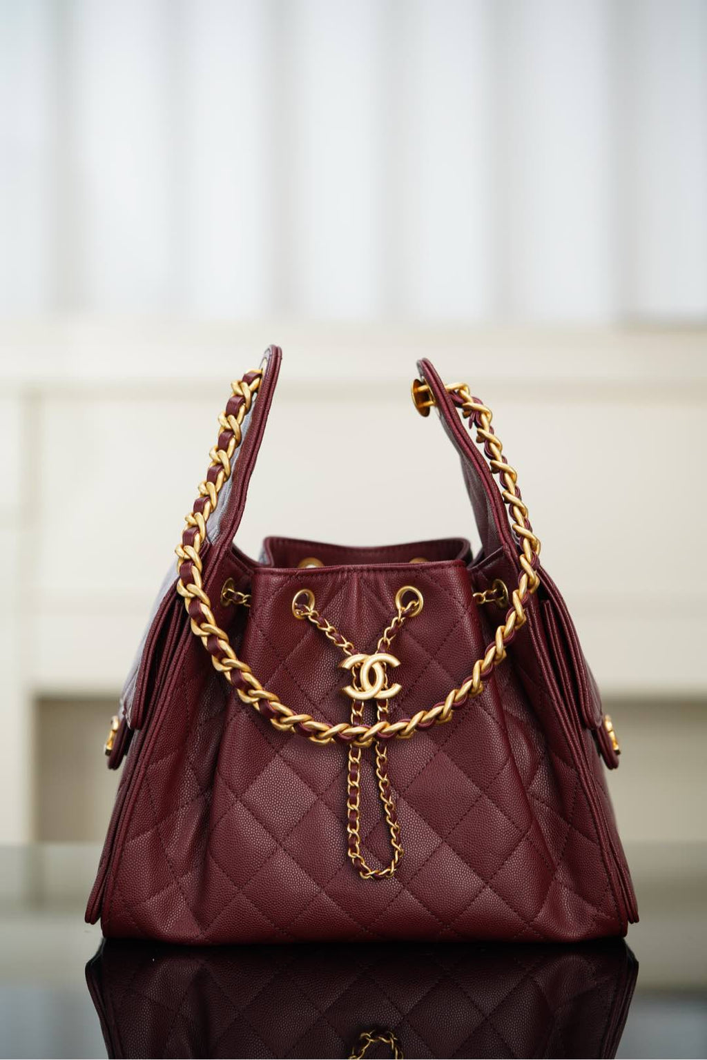 Chanel quilted shoulder bag in dark red with gold chain handles and CC logo charm
