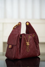 Chanel quilted shoulder bag in dark red, side view with gold chain and CC emblem