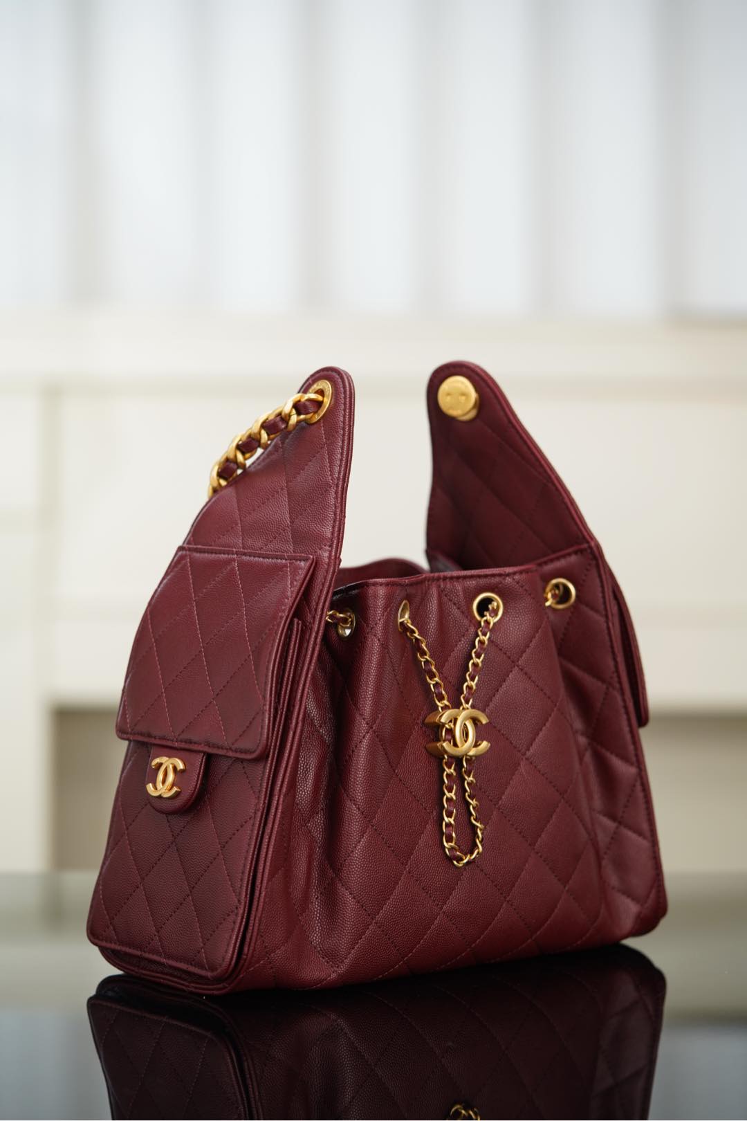 Chanel quilted shoulder bag in dark red, side view with gold chain and CC emblem