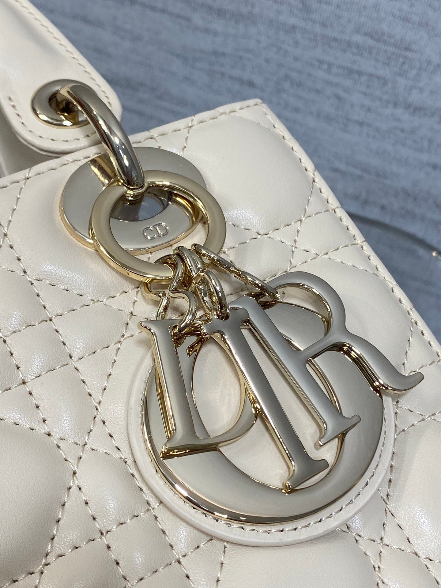 Dior logo charm and metal hardware on quilted handbag strap