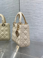 Cream quilted Dior handbag with top handles and dangling charm