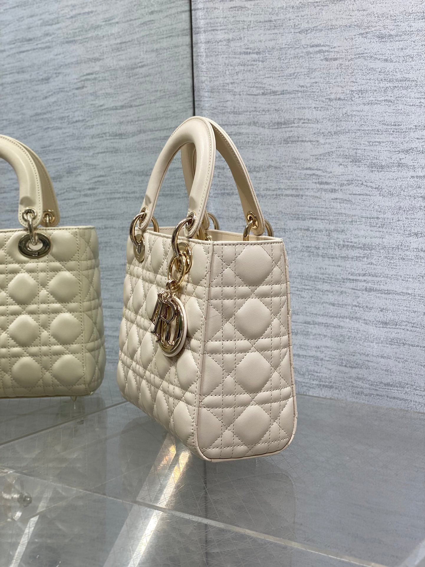 Cream quilted Dior handbag with top handles and dangling charm
