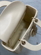 Open white Dior handbag with smooth interior and silver-tone clasp