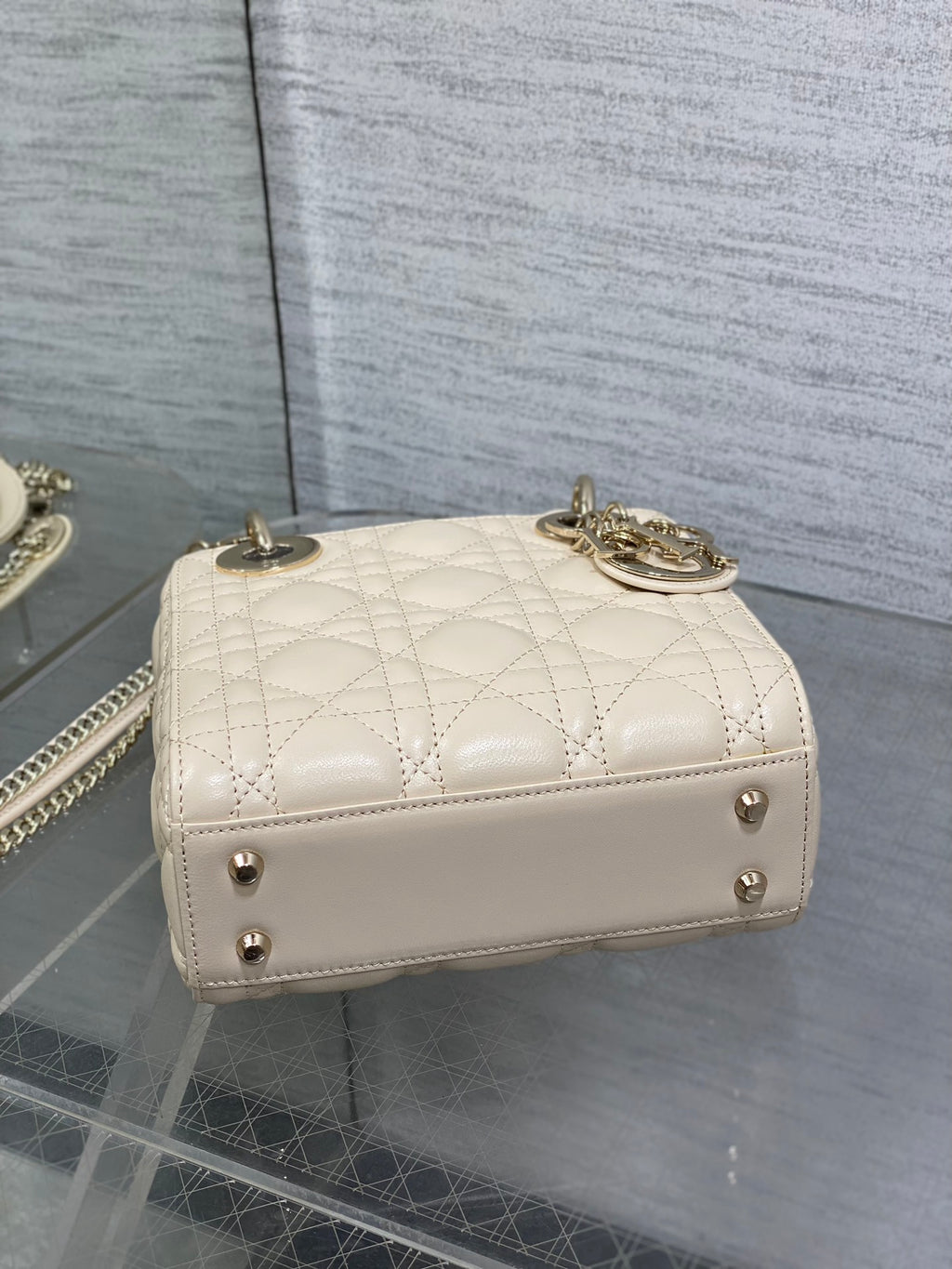 White Dior flap bag with diamond quilted texture, gold-tone studs and top clasp hardware