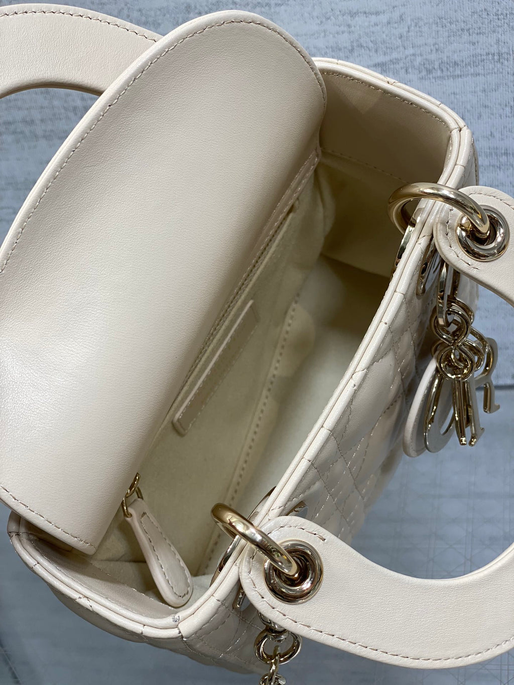 Open white Dior handbag showing interior and top flap with gold-tone ring hardware