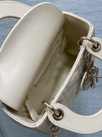 Open white Dior handbag showing interior and top flap with gold-tone ring hardware