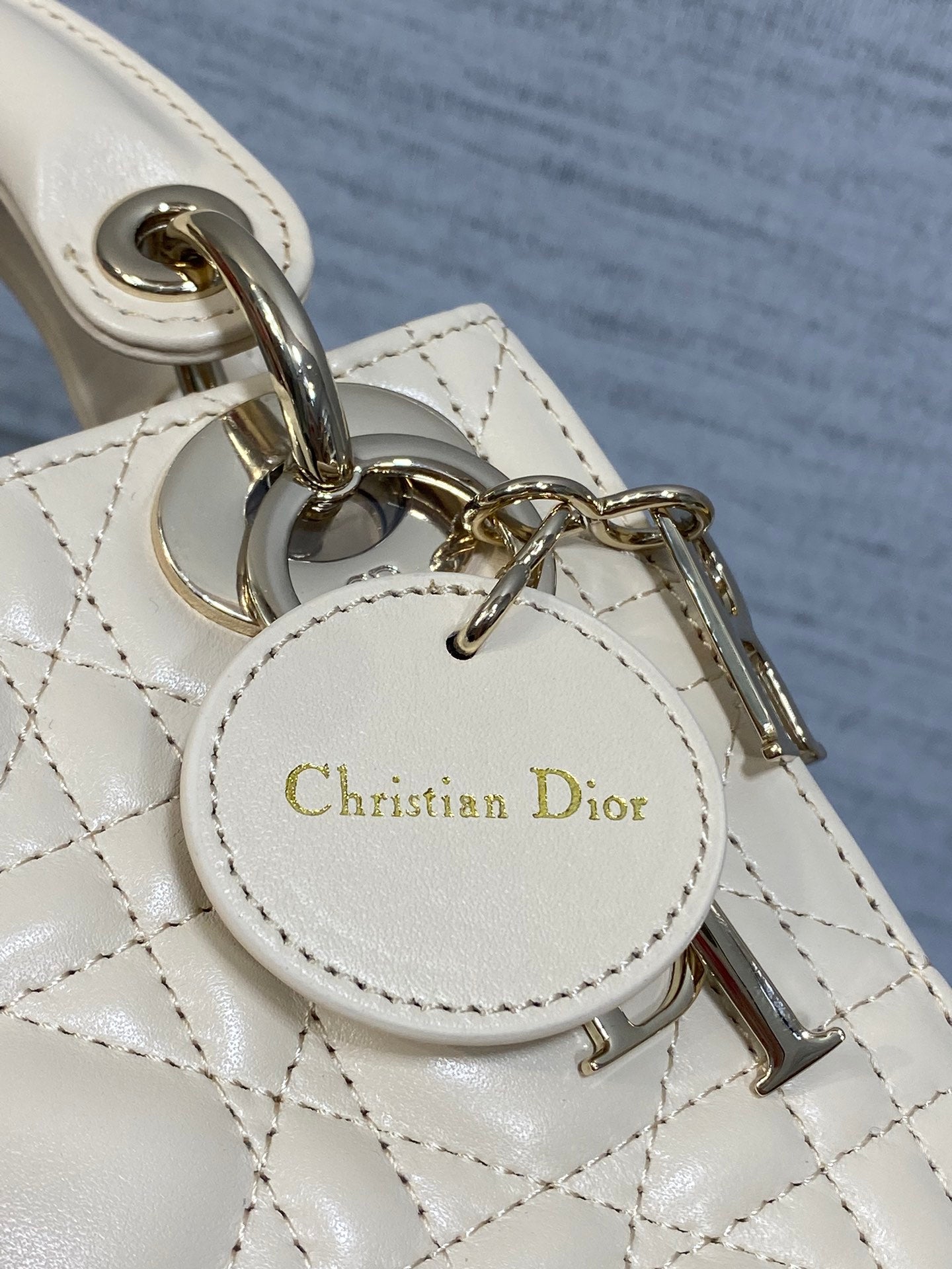 Christian Dior charm tag on white leather strap with gold-tone chain hardware