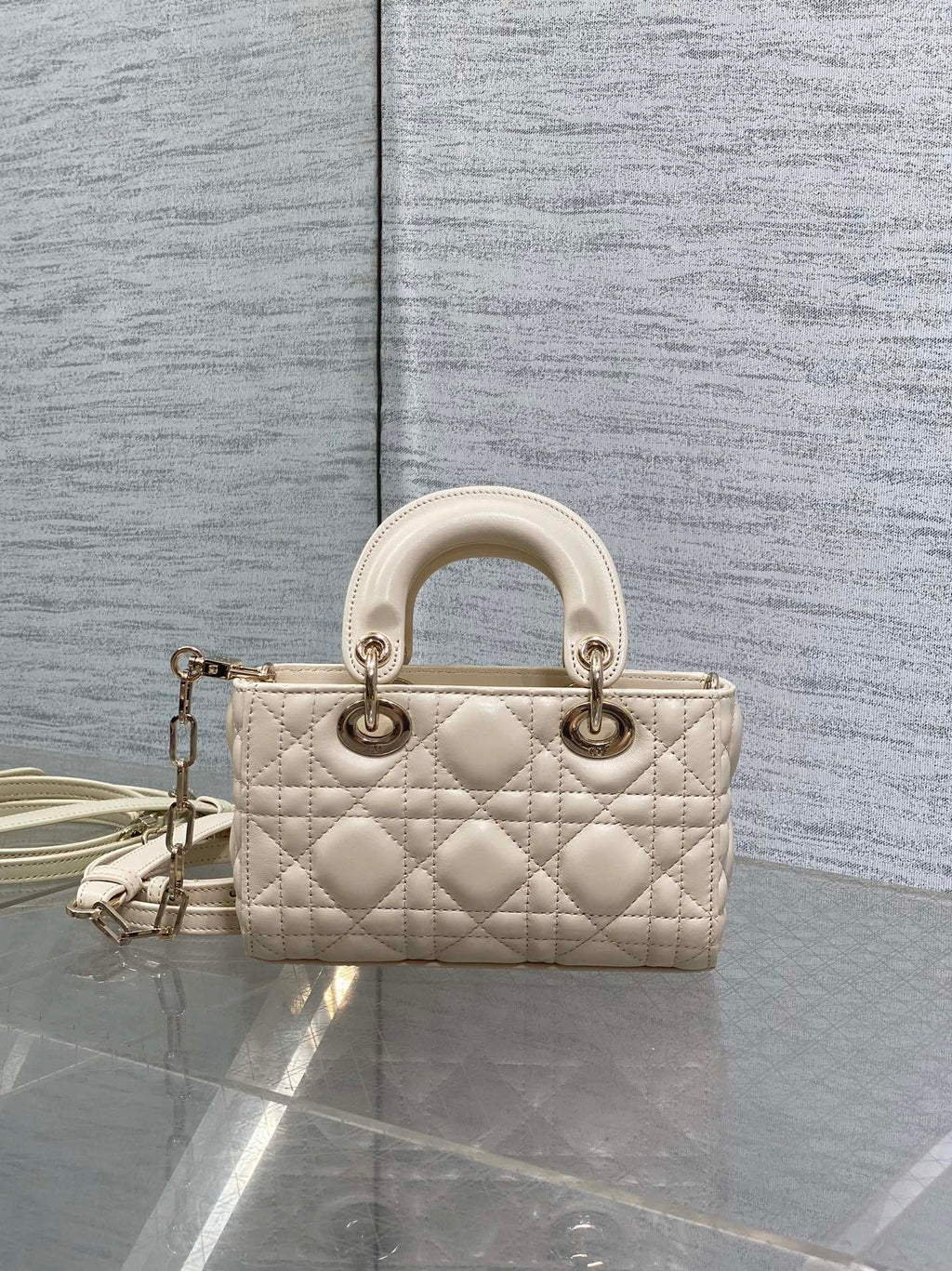 Cream quilted Dior bag with top handles and chain crossbody strap