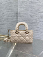 Cream quilted Dior bag with top handles and chain crossbody strap