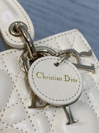 Christian Dior logo charm on cream quilted Dior bag with metal rings
