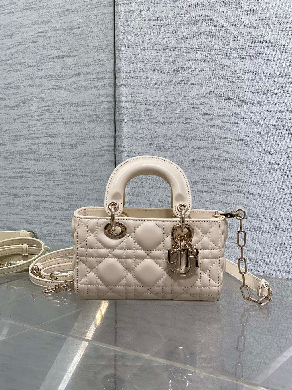 Cream quilted Dior bag with top handles and dangling chain strap