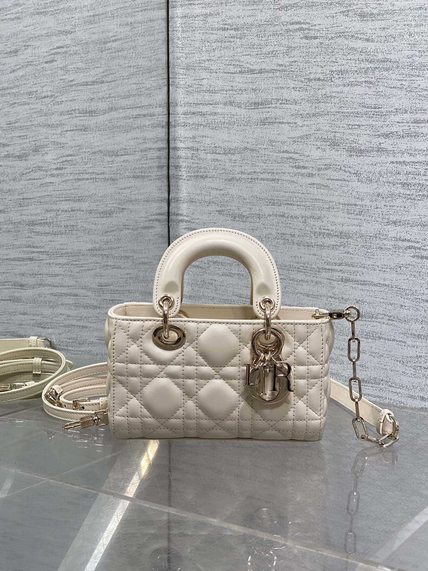 Cream quilted Dior bag with top handles and dangling chain strap