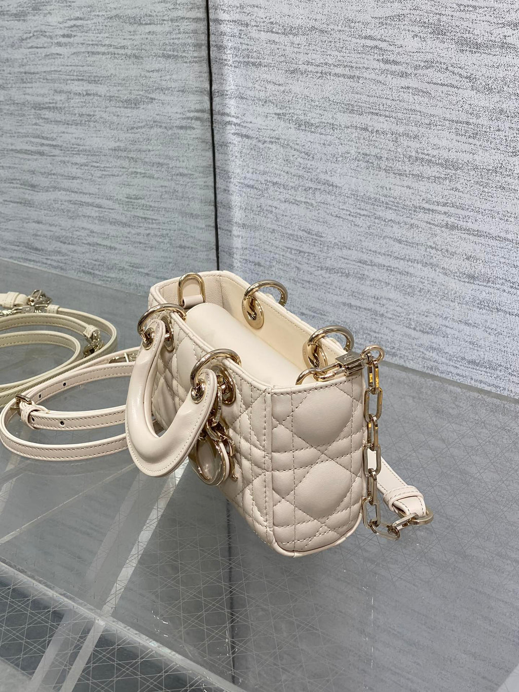 Cream quilted Dior bag with short top handle, crossbody strap, and gold hardware