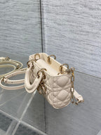 Cream quilted Dior bag with short top handle, crossbody strap, and gold hardware