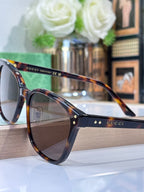 Gucci sunglasses with tortoise front, navy temples, and brown tinted lenses