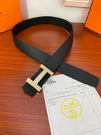 Hermes belt with black textured strap and gold-tone H buckle
