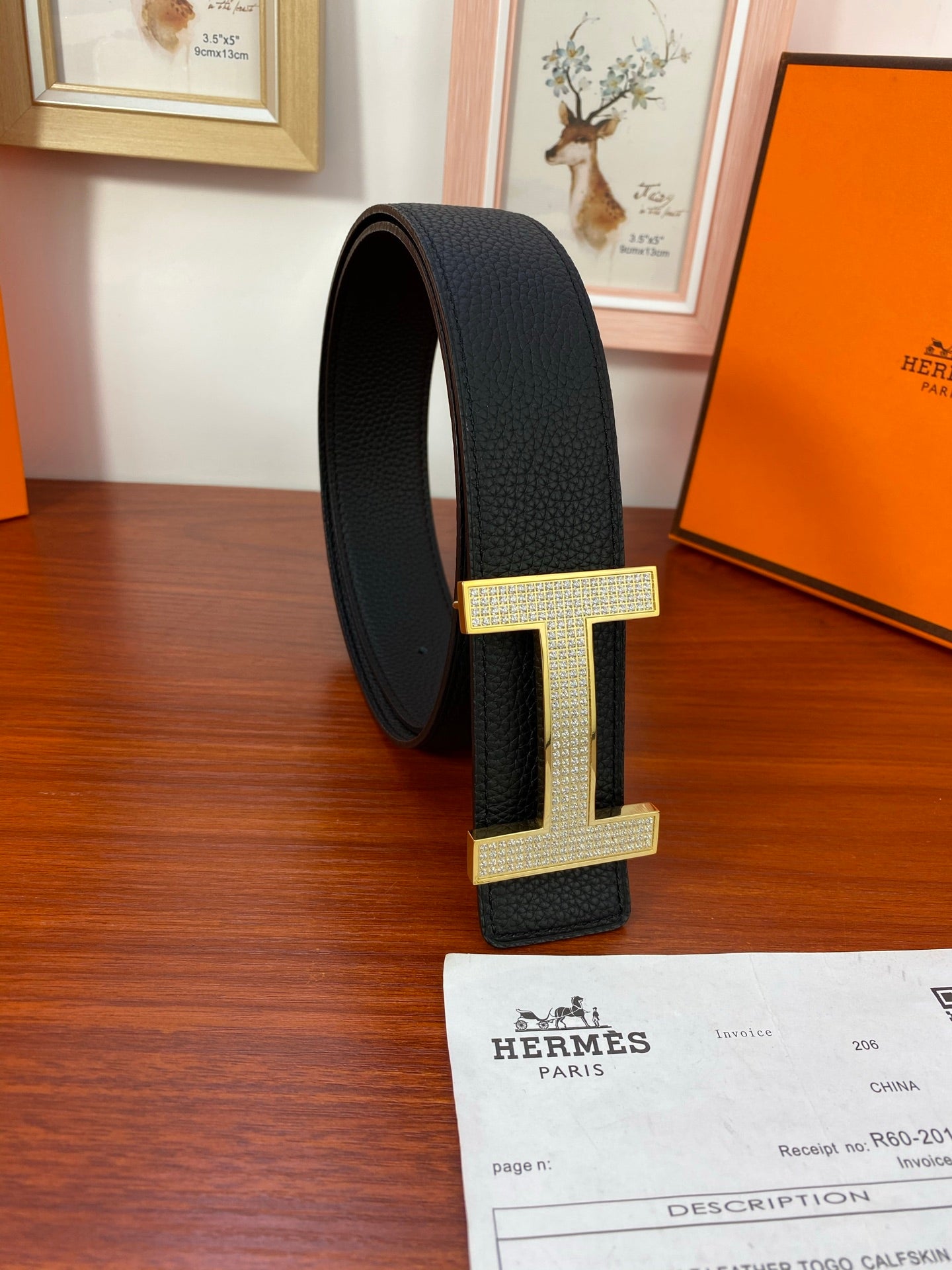 Hermes belt with black strap and gold-tone H buckle on side view