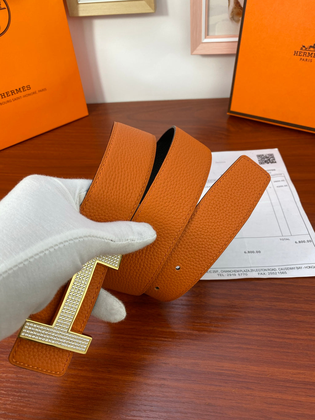 Orange leather belt with black underside and silver-toned studded H buckle
