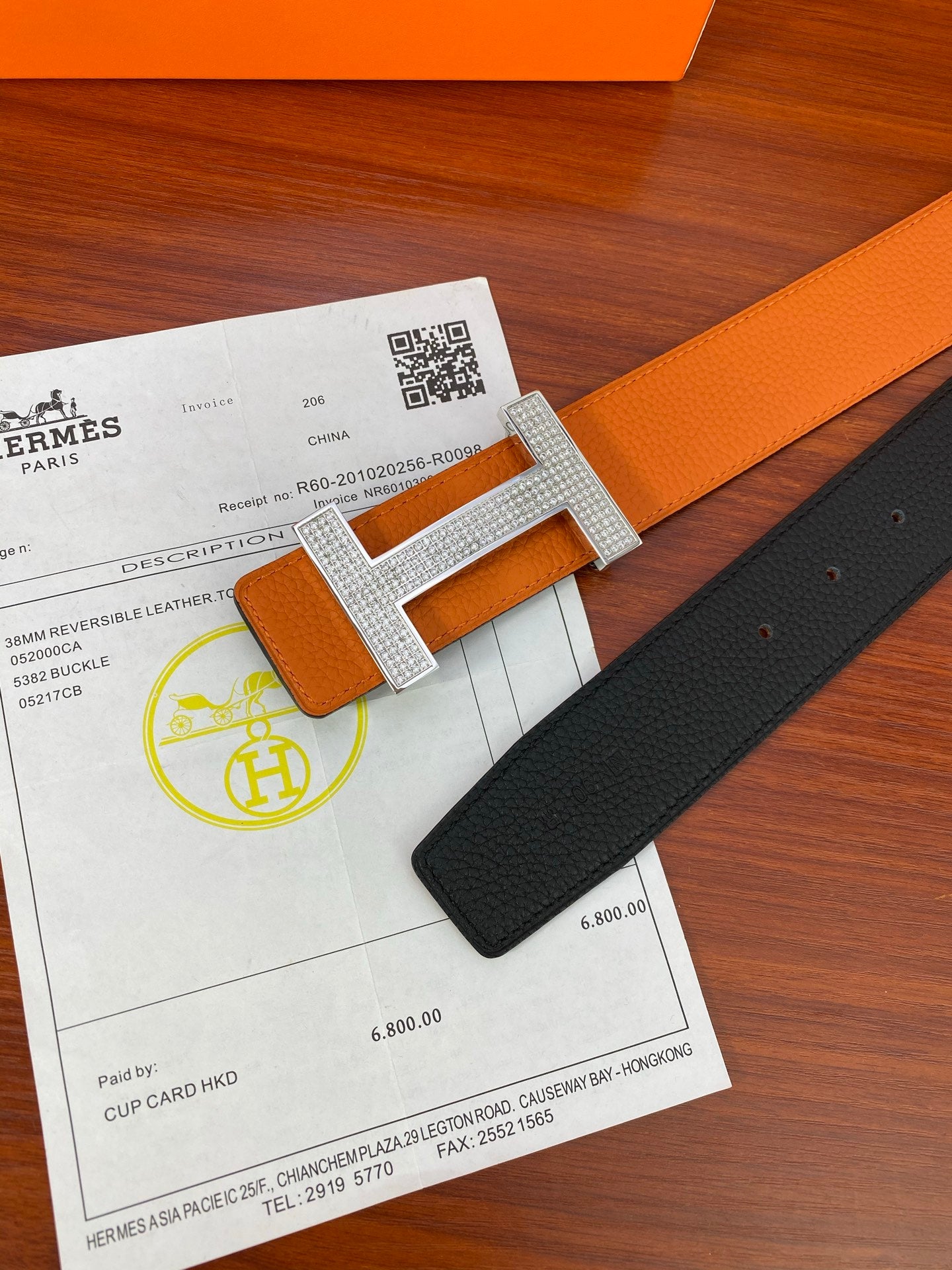 Close-up reversible leather belt with silver studded H buckle on orange strap
