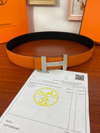 Orange leather belt with black edge and silver-toned studded H buckle
