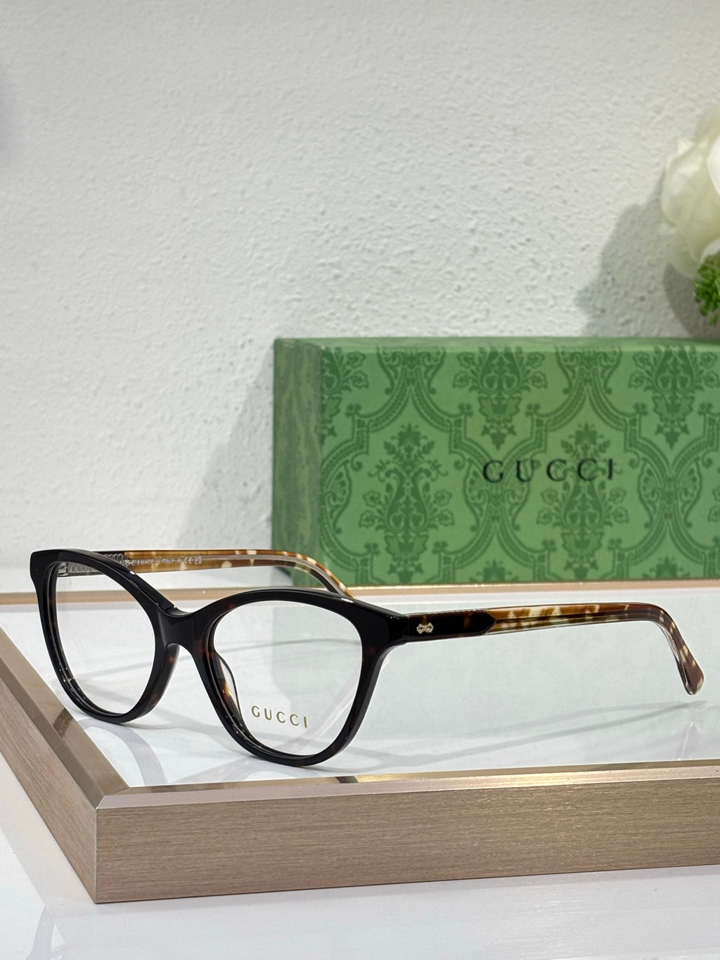 Gucci eyeglasses with black frames, gold-tinted temple arms, and clear lenses