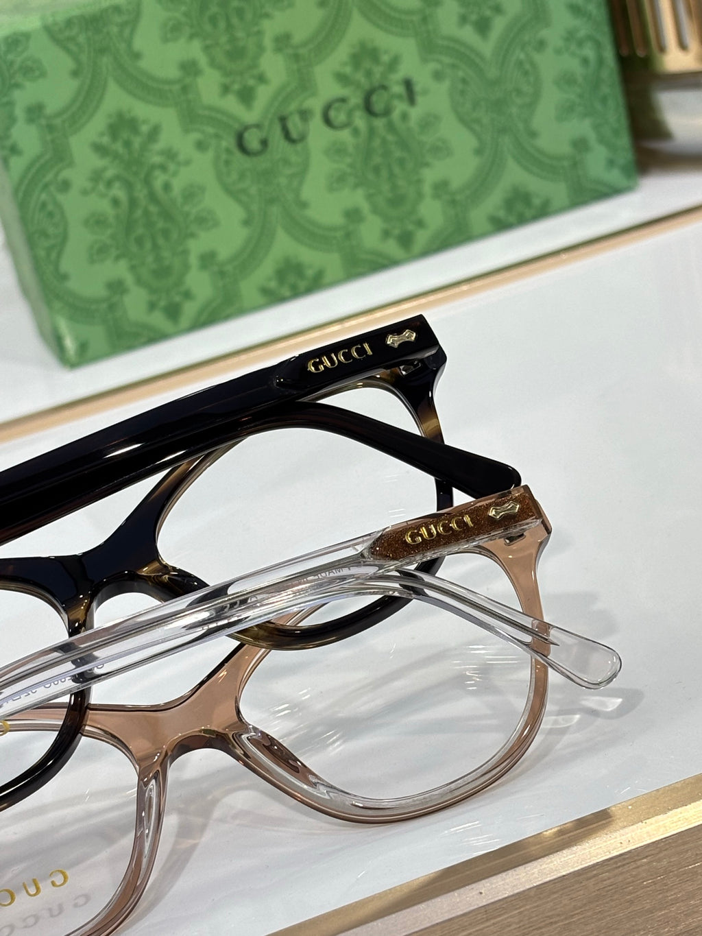 Gucci eyeglasses close-up showing black and gold-toned frames with clear lenses