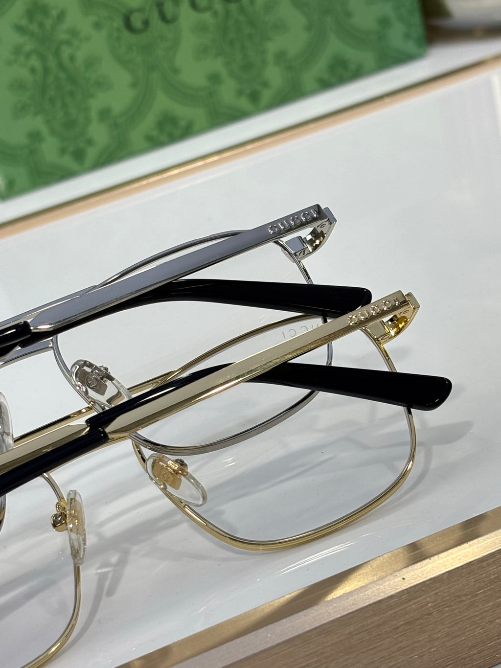 Gucci eyeglass frames shown from side with gold-toned hinges and clear lenses