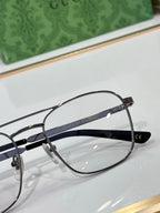 Gucci eyeglass close-up with clear lenses and dark top bar, metal logo text