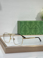 Gucci eyeglass frames with clear lenses, gold temples and dark upper rim