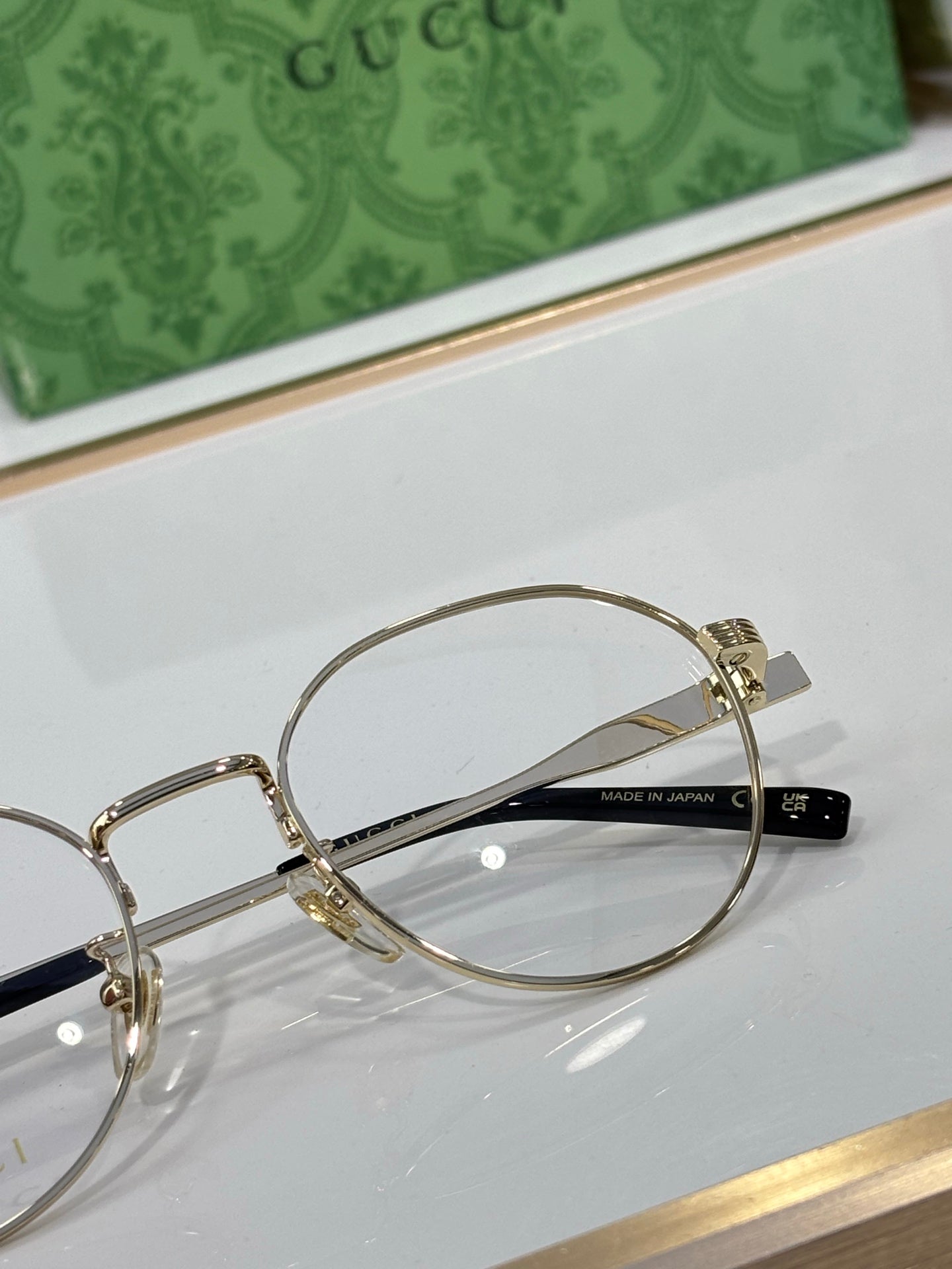 Gucci glasses close-up: gold metal round frame with clear lenses, side logo