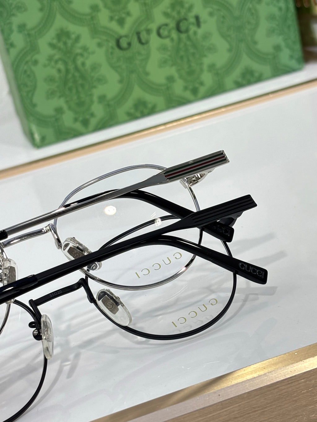 Gucci glasses close-up: black round frame with clear lenses, striped temple detail