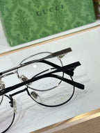 Gucci glasses close-up: black round frame with clear lenses, striped temple detail