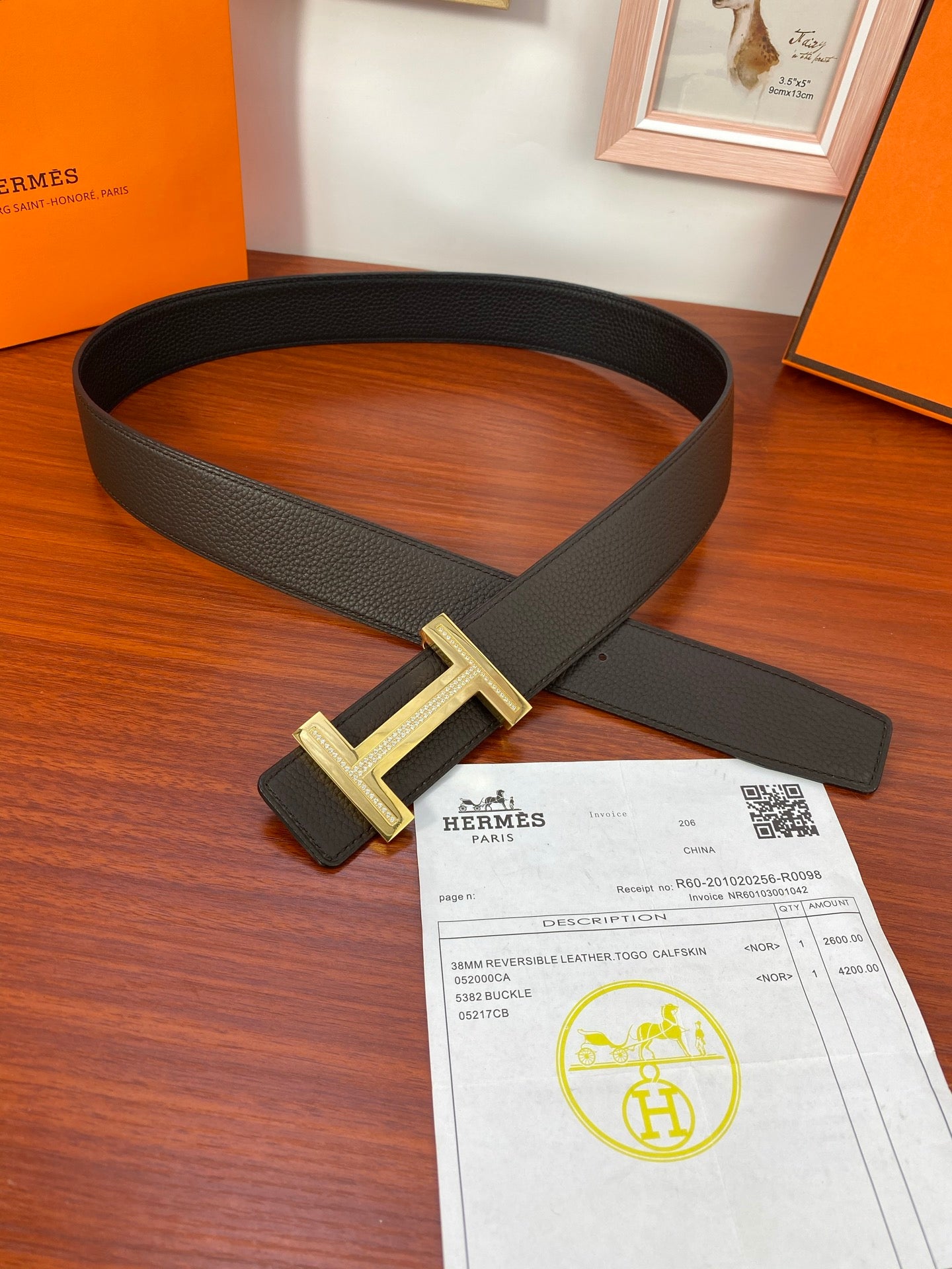 Black textured belt with gold-tone H buckle and matching label tag, with receipt