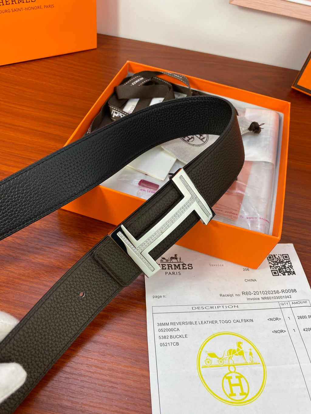 Black belt with silver-toned buckle resting in orange box beside receipt