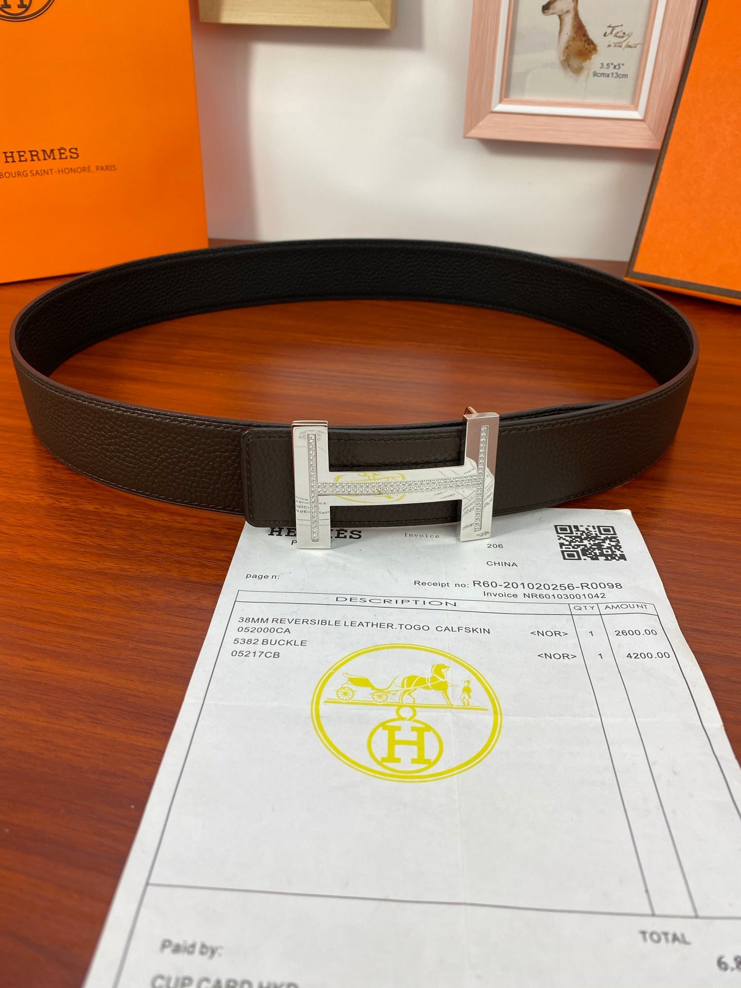 Black textured belt with silver-toned buckle and receipt with QR code