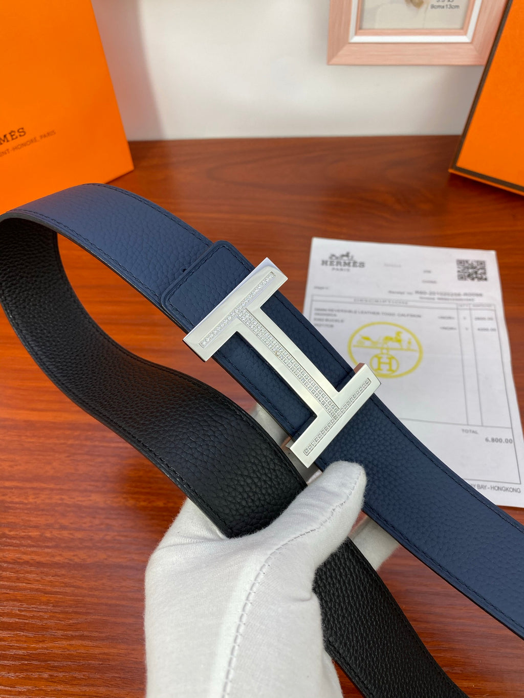 Dark blue leather belt with silver-tone buckle, laid flat on a surface.