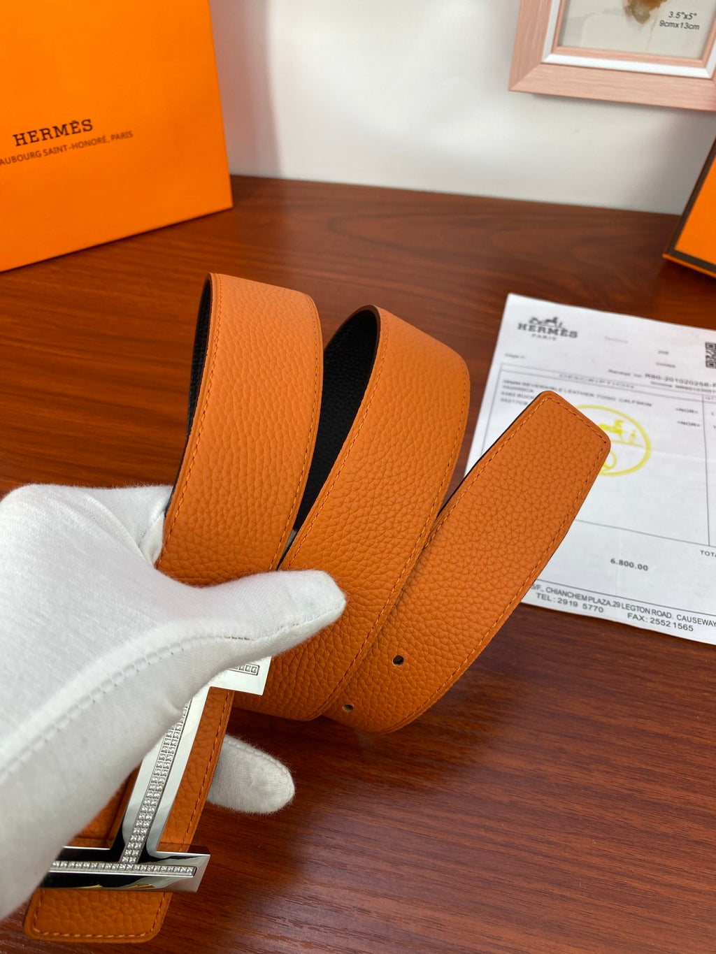Orange leather belt end with silver-tone buckle hardware and black reverse panel.