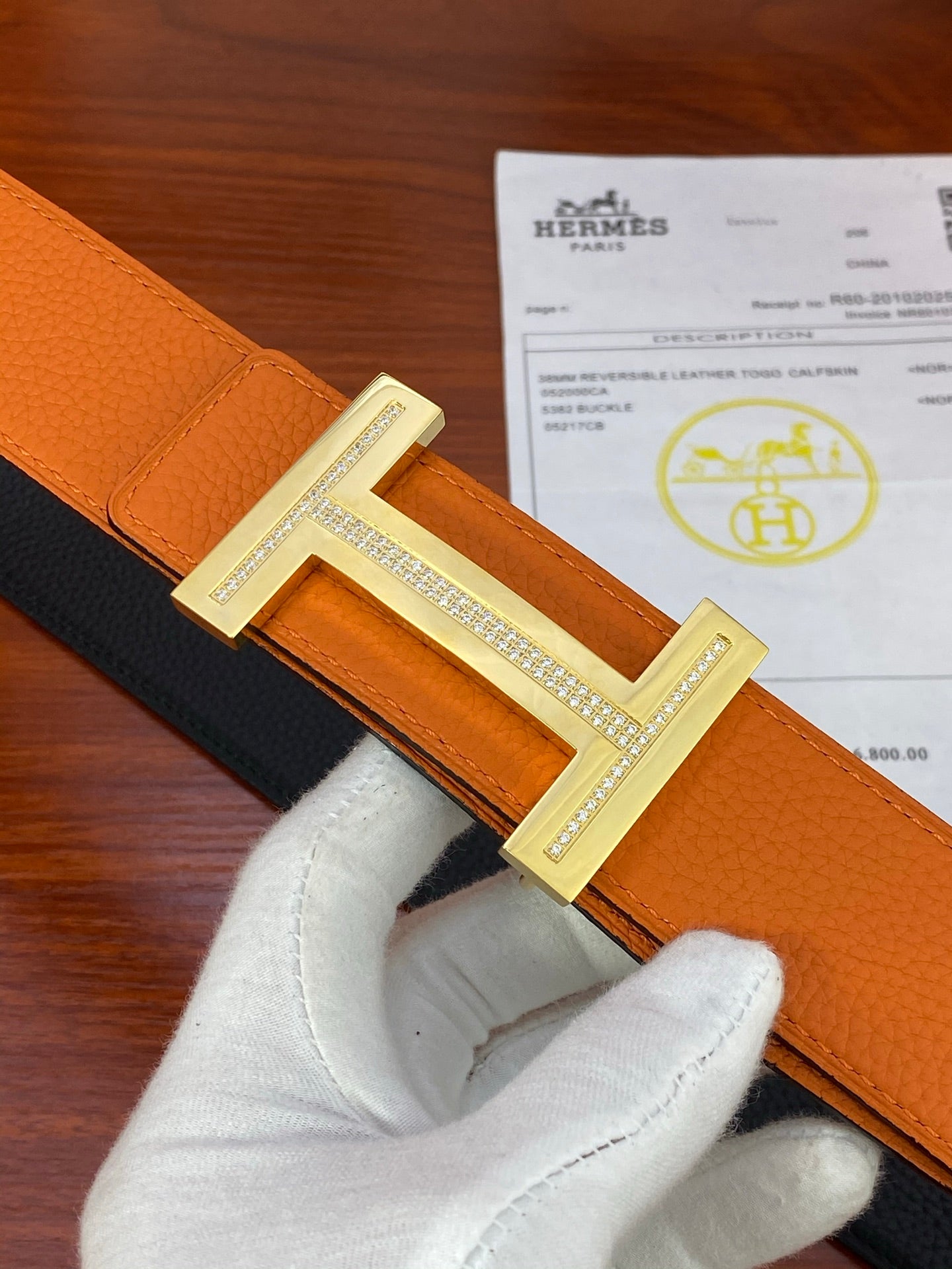 Reversible belt close-up: orange leather with black side and silver-tone buckle.