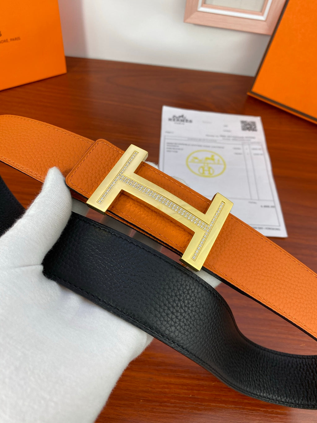 Reversible belt detail: orange leather with black side and silver-tone buckle.