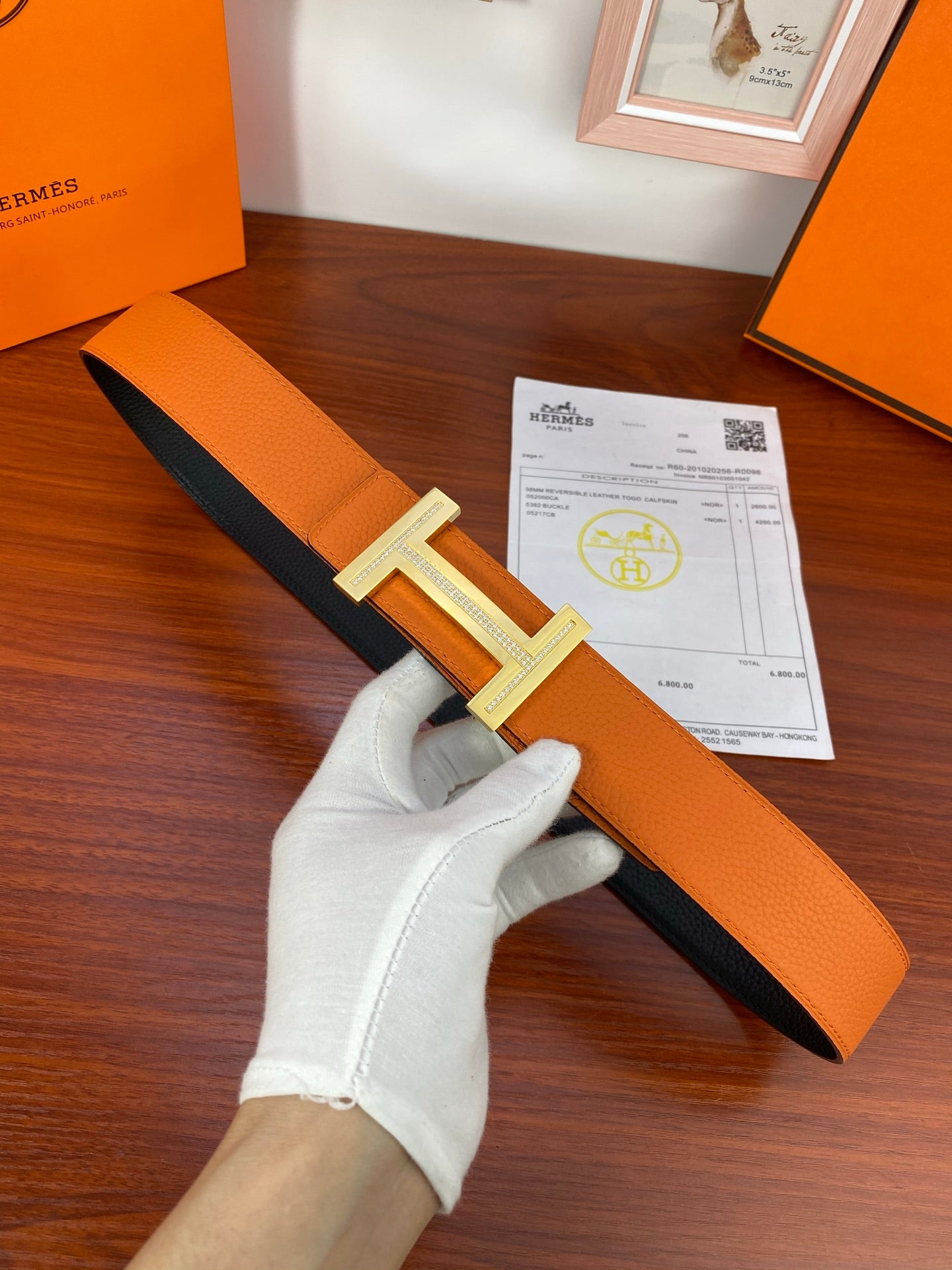 Reversible leather belt, orange with black backing, and silver-tone H buckle.