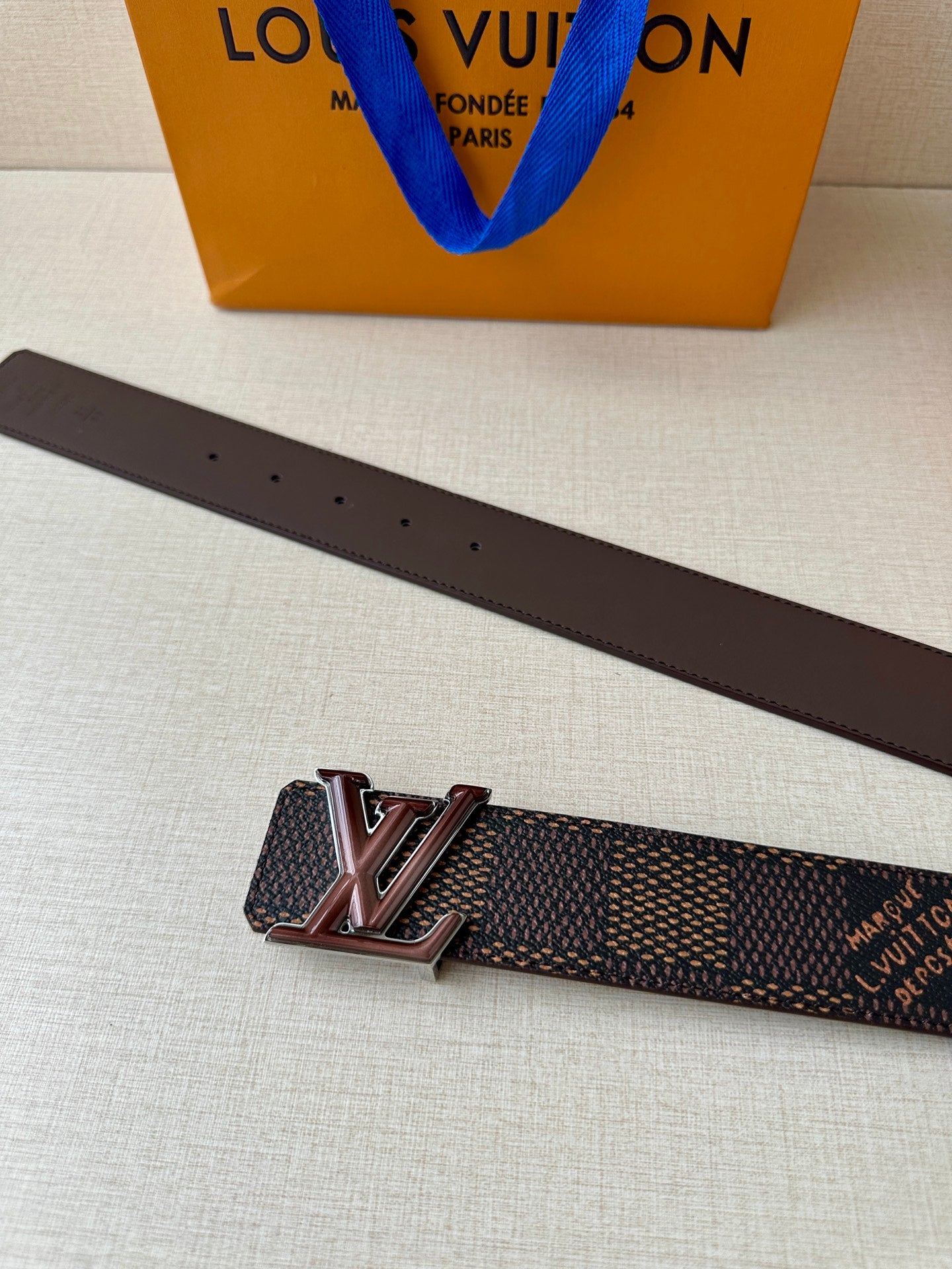 LV belt strap with brown leather back, stud holes, and metal buckle