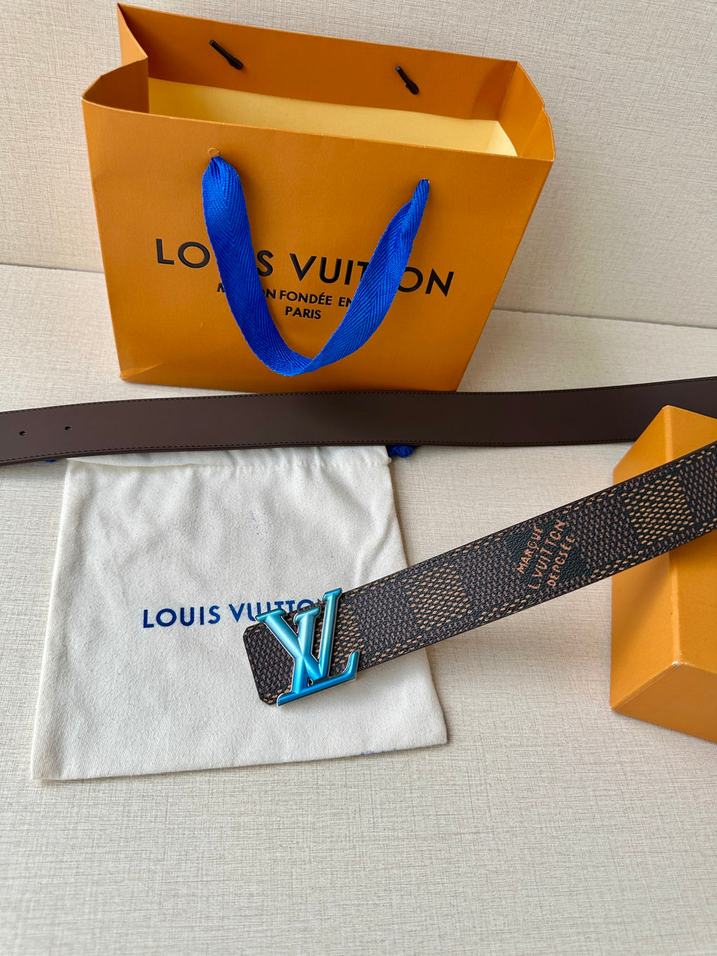 Louis Vuitton belt across white pouch, dark monogram with blue LV buckle