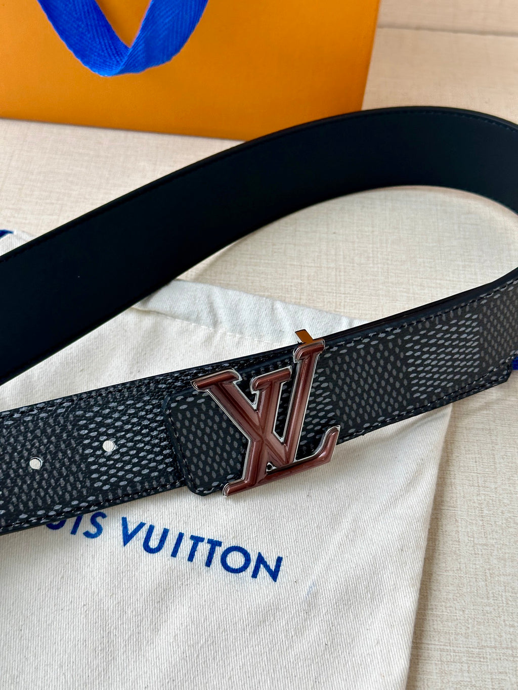 Louis Vuitton belt close-up with LV logo buckle and perforated adjustment holes