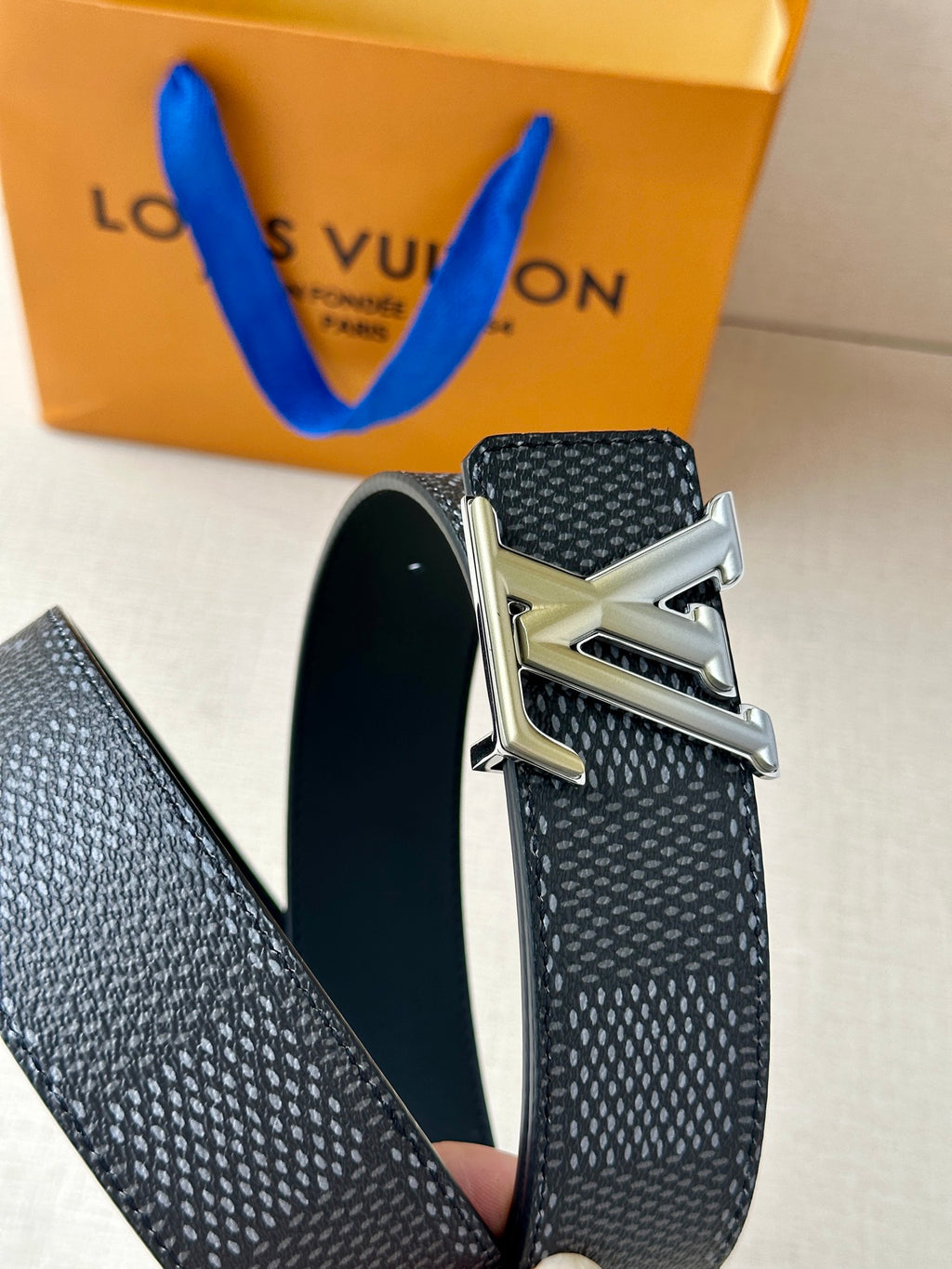 Dark textured Louis Vuitton belt with silver-tone LV buckle and angled strap end