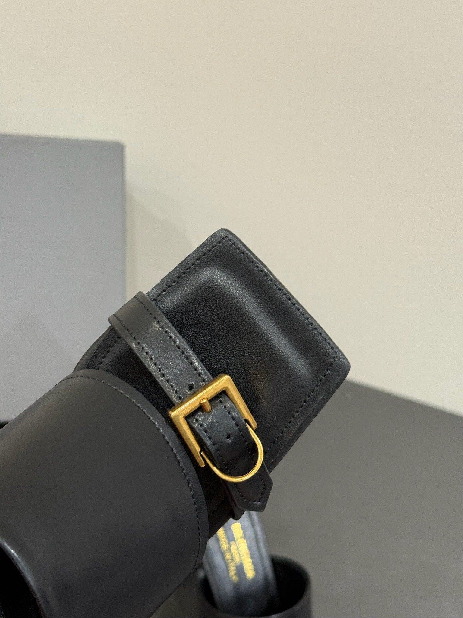 Black leather sandal strap with square gold buckle detail
