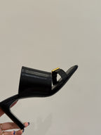 Black leather mule sandal with gold buckle strap, side view of heel